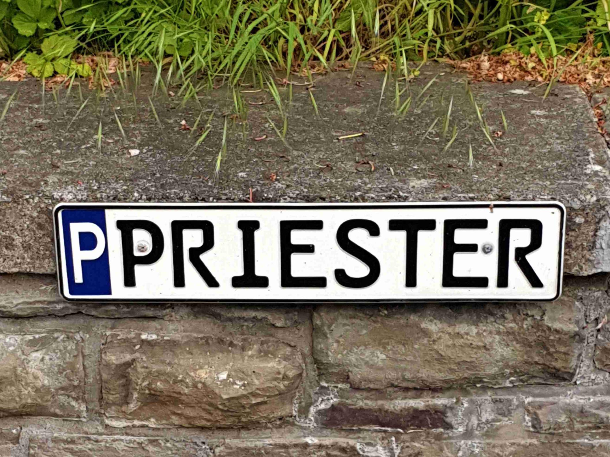 Ein Schild weist einen Parkplatz für den Priester aus.
