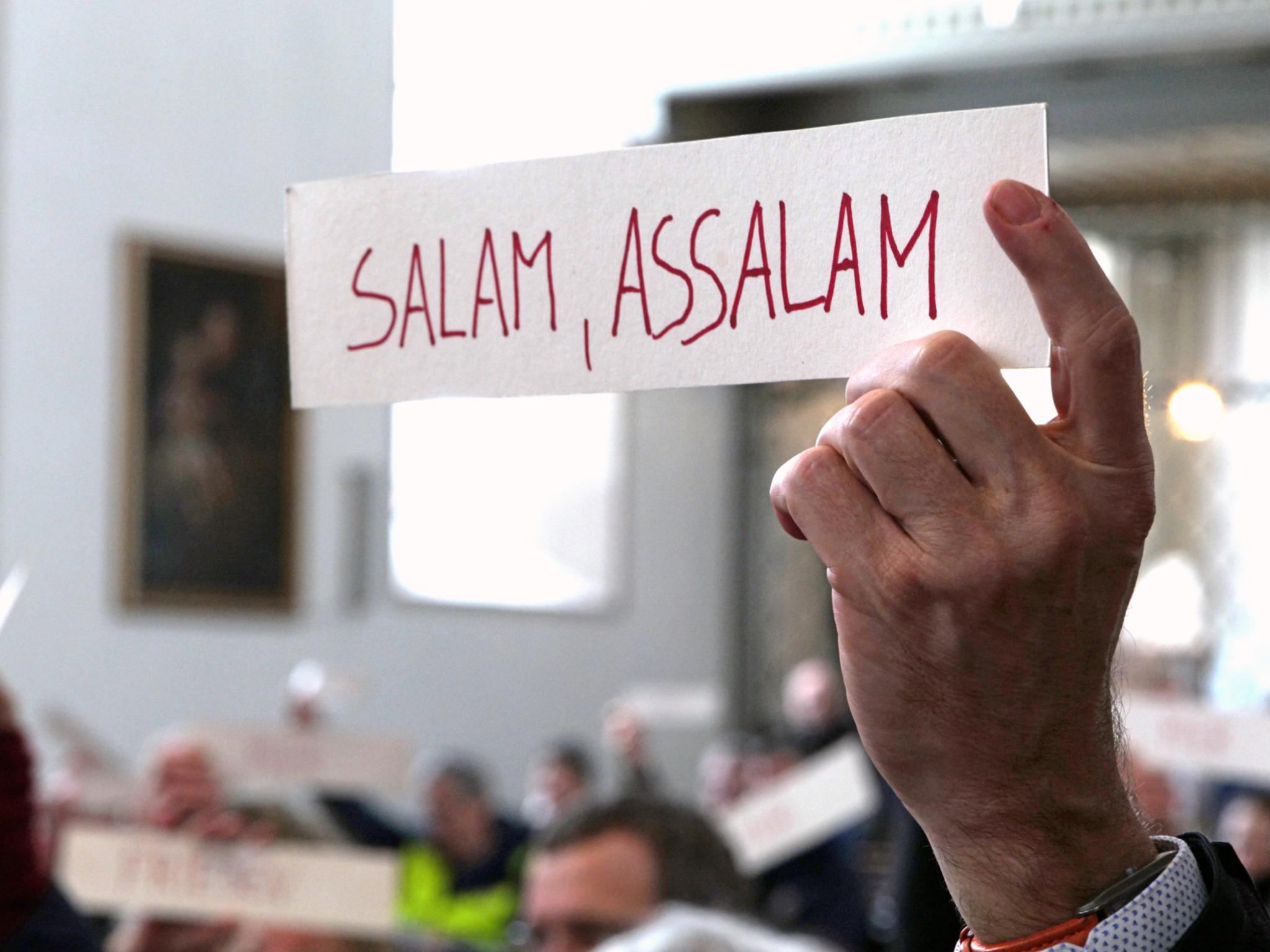 Hand hält Schild mit der Aufschrift 'Salam, assalam'
