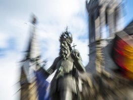 Verwischtes Bild der Statue Kaiser Karls vor dem Aachener Rathaus mit Europaflagge und Deutschlandflagge)
